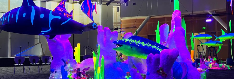 Spotted eel and giant tiger shark standoff in a black light sculpture art installation